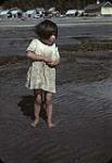 Une fille des Premières Nations debout sur la berge d'une rivière [1947]