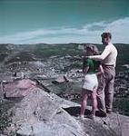 Bob Marshall and Ruby Fillotre at the edge of a cliff looking at Bowater's Newfoundland pulp and paper mill in Corner Brook July 1949