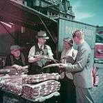 Des touristes se renseignent sur le tabac cultivé au Canada, au marché Bonsecours, à Montréal juin 1950