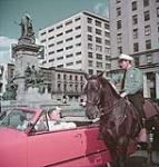 Un policier à cheval donne des instructions à des touristes au carré Philipe à Montréal July 1950