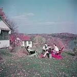 One man, two women and a young boy seated outdoors on an autumn day a a summer cottage on the Gatineau River, Québec, north of Ottawa, Ontario octobre 1950