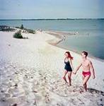 Two bathers - one man and one woman - walk hand-in-hand up sand dunes near Picton overlooking lake Ontario août 1951