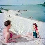 Deux baigneurs - un homme et une femme - sont étendus sur les dunes près de Picton au-dessus du lac Ontario août 1951