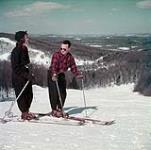 Un homme et une femme font du ski sur les collines de la Gatineau au Québec au Nord d'Ottawa, en Ontario mars 1952