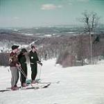 Deux hommes et une femme font du ski, Collines de la Gatineau au Québec, au nord d'Ottawa mars 1952