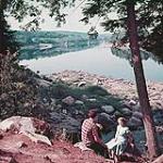 Man and woman sitting on the bank of the St. John River near Hartland, New Brunswick  Un homme et une femme assis sur la berge de la rivière St-Jean près de Hartland, au Nouveau-Brunswick 1952