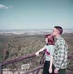 Mr. and Mrs. G. Dooley, of Bismarck, North Dakota, at Norgate Lookout Tower, Riding Mountain National Park, Manitoba  [M. et Mme G. Dooley, de Bismarck, au Dakota du Nord, à Norgate Lookout Tower, au parc national du Mont-Riding, au Manitoba] 1952