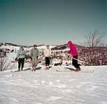 Trois skieurs écoutent des instructions sur les pentes au-dessus de Ste-Agathe, au Québec février 1953