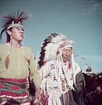 Indians of the Blood Indian tribe costumed for their annual Sun Dance ceremony at the Blood Indian Reserve near Cardston, Alberta. [Les indiens du tribu indien Blood en costume pour la cérémonie annuel du Sun Dance à la Reserve indienne Blood près de Cardston, Alberta.] août 1953