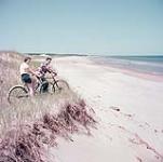 Man and woman on bicycles at the beach, Prince Edward Island National Park July 1953