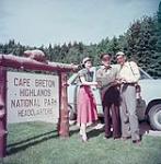 Un homme et une femme consultent une carte avec l'aide d'un employé du parc national des Hautes-Terres du Cap-Breton, en Nouvelle-Écosse July 1953