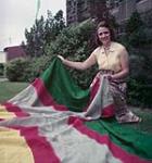 Woman on grass with large tapestry, Saguenay River August 1954