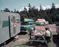 People having a picnic in a campground in Prince Edward Island.  [Piquenique dans un terrain de camping à l'Île-du-Prince-Édouard] 1956