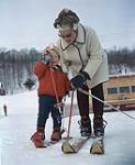 Lucille W. Vaughan and her daughter Merle, a mini-midget, with skis on. Midget Skiing (probably Camp Fortune) s.d.