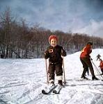 Jeune skieur portant un chapeau rouge en skis (Schuss?). Mini-ski (probablement Camp Fortune) n.d.