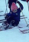 Fallen young skier wearing a pink hat trying to get up. Midget Skiing (probably Camp Fortune) février 1964