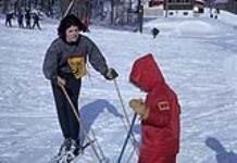 Ski instructor Pat Kidd encourages a reluctant young skier. Midget Skiing (probably Camp Fortune) February, 1964