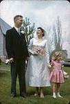 Anna and John on their wedding day, with a girl in a pink dress [entre 1955-1963]
