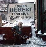 Fille pelletant de la neige devant des affiches publicitaires, ville de Québec [entre 1955-1963]