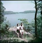 Strolling along the shore of Lake Rosseau near Wigwassan Lodge in the Muskoka Lakes district, Ontario.  juillet 1951.