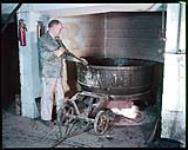At the Ottawa Paint Works, varnish maker Jack Davison operates the varnish kettle. [Au «Ottawa Paint Works», le fabricant de vernis Jack Davison utilise le bouilloire de vernis.] janvier 1955.