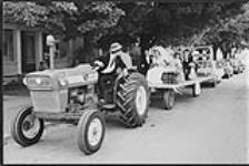 Wedding party on a flat-bed trailer being pulled by a Ford tractor, Toronto [ca. 1955-1976]