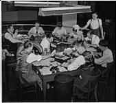 Globe and Mail, workers in the newspaper rooms, Toronto, writers and editors working at a table [ca 1939-1951]