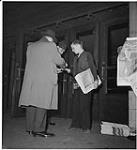 Globe and Mail, workers in the newspaper rooms, Toronto, men buying a newspaper from a paper boy [ca. 1939-1951]