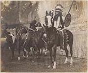 [Group of First Nations Men on Horseback in Front of Painted Backdrop from Buffalo Bill's Show]. Original title: Indians on Horseback in Front of Painted Backdrop from Buffalo Bill's Show 1887