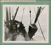 Nine men on a ship in winter lifting a large conical gas buoy, St. Lawrence River n.d.
