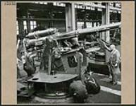 Group of men work in factory manufacturing Bofors Twin Oerlikon gun mounts during WWII at the Regina Industries factory 1944