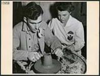 Madame J. Alouise, ergothérapeute à la salle de poterie de Scarboro Hall, observe le cavalier G.W. Galbraith de Toronto, qui a passé cinq ans dans le corps de chars, travailler sur une chope, à Toronto March 1945