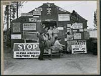 George Uffendell de l'ARC, originaire de Whangarei en Nouvelle-Zélande, et John Ferguson, originaire de Havelock North en Nouvelle-Zélande, installent une nouvelle affiche dans les baraques pour les Néo-Zélandais à Watson Lake, dans le cadre de la ligne d'étapes du Nord-Ouest September 1944