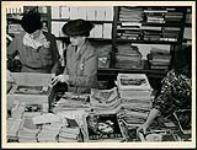 Two female volunteer workers at the London Ontario public library sort and pack books and magazines for the men and women of Canada's armed services March 1945