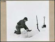 A fisherman lowers his line into a hole in the ice March 1945