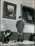 Young boy watches a young girl work on the floor at a Saturday morning art class held at the Vancouver Art Gallery March 1945