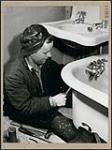Plumber James P. Griffiths working in a customer's bathroom April 1945