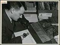 Lloyd Edwards écrit dans un registre à l'aide d'une main artificielle, à la English Electric Co., à St. Catherines April 1945