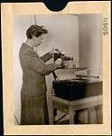 Woman setting up device on top of a turntable in the National Film Board's Filmstrip Section, Ottawa February 1945