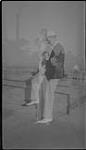 Wilson P. MacDonald holding Ann MacDonald, leaning on a stone wall [1940]
