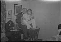 Ann MacDonald assise sur les cuisses de Wilson P.; tous les deux assis à un bureau [1955]