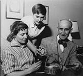 Wilson P. MacDonald, Dorothy Ann MacDonald and Ann MacDonald at home, looking at Viewmaster slides [1968]