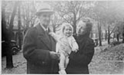 Wilson P. MacDonald and Dorothy Ann MacDonald holding Ann MacDonald on a front lawn [1940]