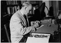 Wilson P. MacDonald working at a desk [1960]