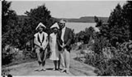 Wilson P. MacDonald and two women wearing paper hats, at Muskoka [1926]