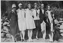 Wilson P. MacDonald et cinq femmes appuyés sur un mur de pierres [1926]