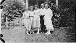 Wilson P. MacDonald and four women standing on a lawn in front of a house [1920]