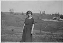 Woman standing in front of a hilly landscape [1925]