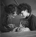 [Joyce Driver immunizing a Métis baby held by an older sister] September 1953