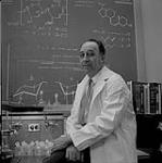 [Dr. Bert Migicovsky perched on the edge of a desk in a lab] [ca. 1962]